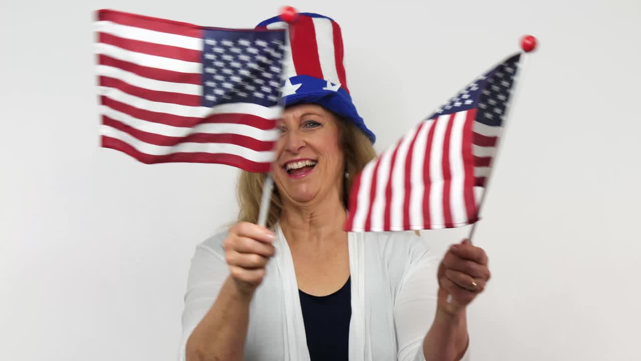 A senior redhaired woman sways two flags in patriotic celebration
