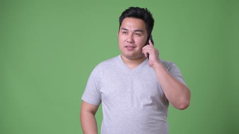 초록색 배경에 젊은 잘생긴 과체중 아시아인