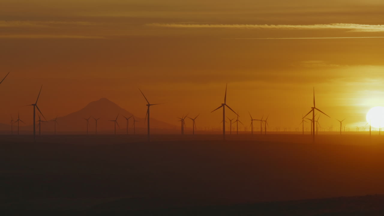 Wind Turbines Backlit With Bright and Golden Sunset At Wind Farm In Oregon, USA. - wide panning