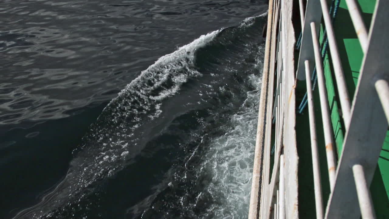 lado del ferry que viaja por el océano azul dejando una estela y olas en la superficie