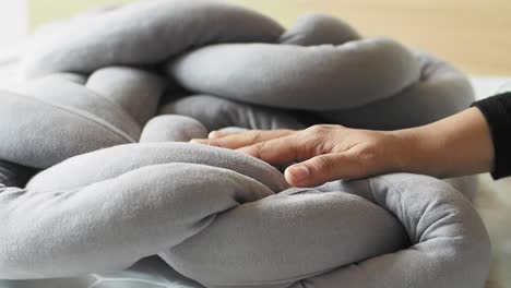 grey knotted pillow with hand