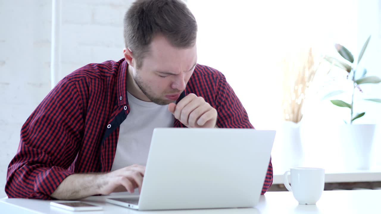 joven enfermo toser y trabajar en la computadora portátil, infección de la garganta