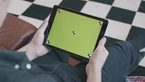 persona que sostiene una tableta con una pantalla verde