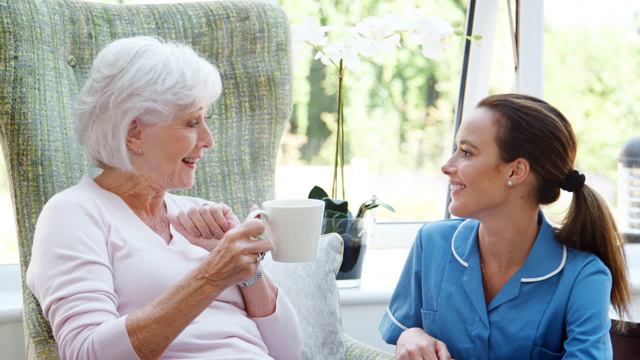 노인 가정 에서 의자 에 앉아 간호사 와 대화 하고 있는 노인 여자