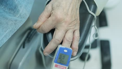 paciente viejo con oxímetro de pulso en el dedo para el monitoreo durante la cirugía en el hospital