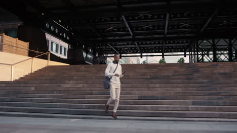 african american businessman walking through city using smart phone