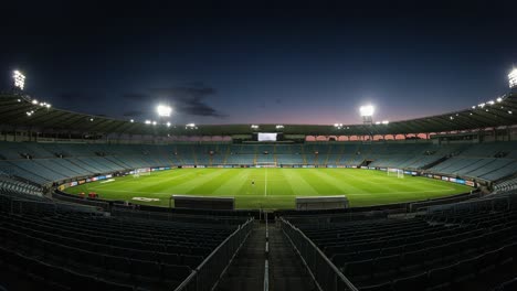 a stunning night view of an empty stadium with illuminated field and bleachers under a dusk sky, showcasing the beauty of sports venue design and architecture
