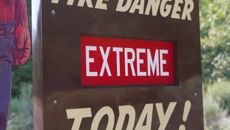 Fire Danger Extreme Today brown with red and white text posted at national park canyon during hot heat wave summer wild fire season, as camera pans up and down, backlit