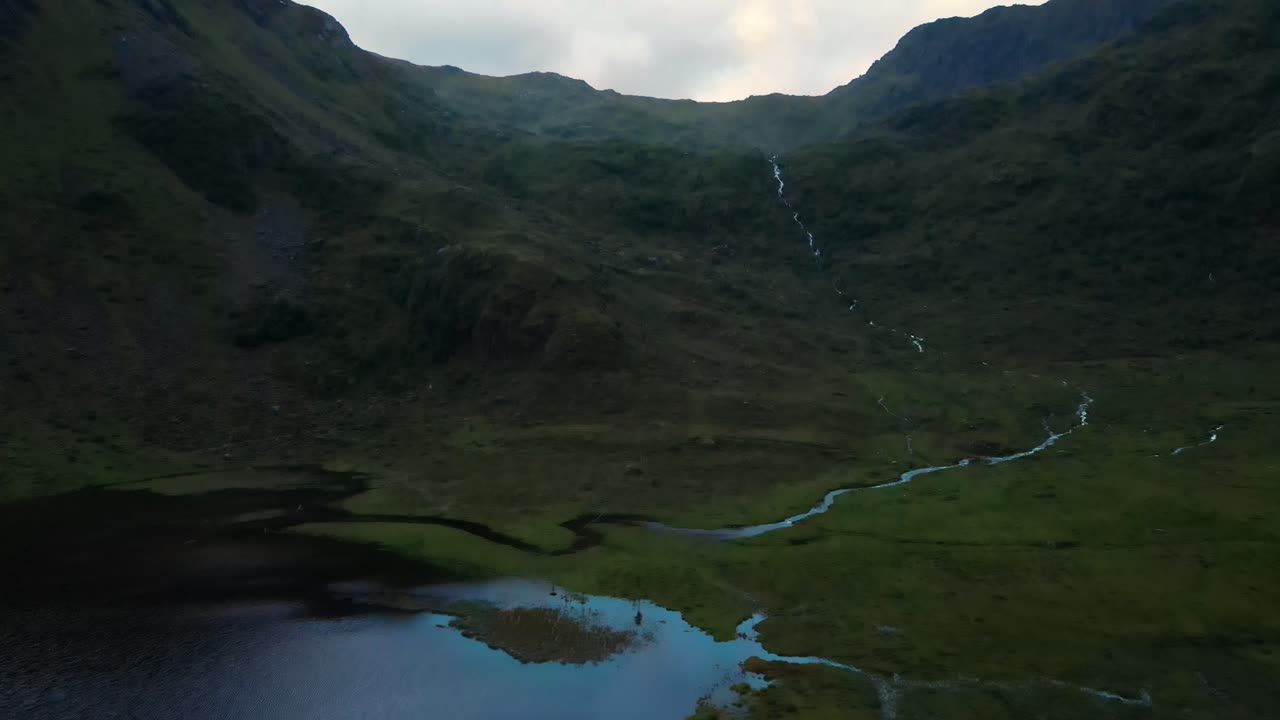 sobrevuelo aéreo del lago justadvatnet y verdes laderas de montañas rocosas en noruega