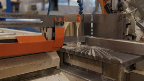 a mechanical saw cutting through a aluminium bar