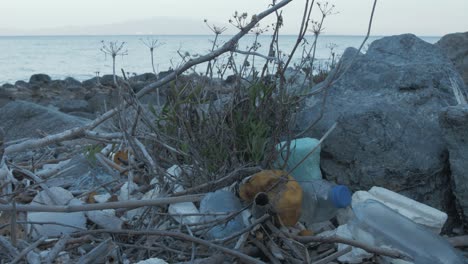 plastic waster washed up along rocky shoreline medium shot