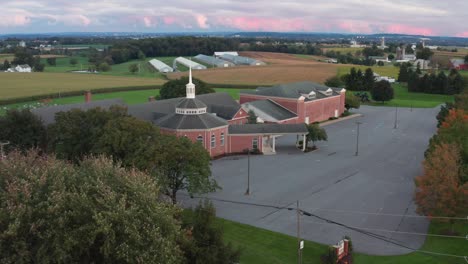 Aerial-of-exterior,-red-brick-Christian-church-and-steeple-in-rural-America