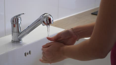mujer lavándose las manos en el fregadero de la cocina