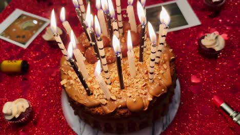 birthday cake with candles and red glitter in background, party celebration