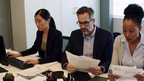 group of professionals engaged in a strategy meeting at a contemporary office. they review documents and discuss tasks while using laptops to enhance collaboration and productivity.