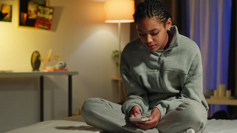 teenage girl using smartphone in her bedroom at night