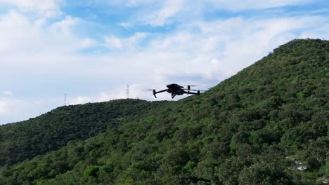 órbita alrededor de la silueta de un quadcopter drone flotando contra un fondo de montaña verde exuberante tropical