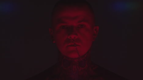 tattooed man with nose chain in dark studio
