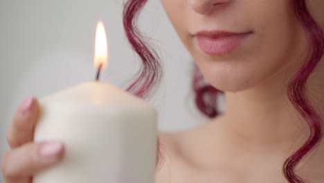 hermosa chica sostiene velas encendidas cerca de la cara, preparación del procedimiento de belleza