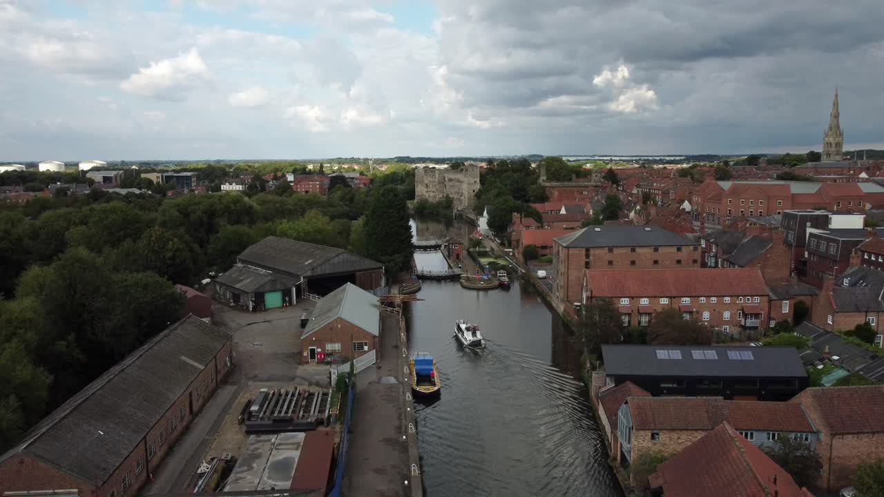 A Drone video of a River Boat heading towards Newark Town Lock. The footage lowers down and captures the building around including g Newark Castle and St Mary Cathedral.
