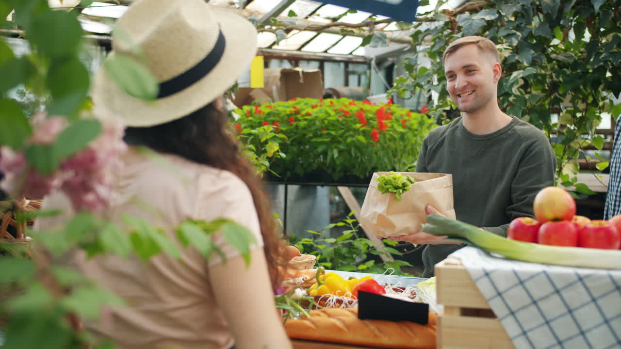 Customer purchasing fresh produce at a farmers market greenhouse