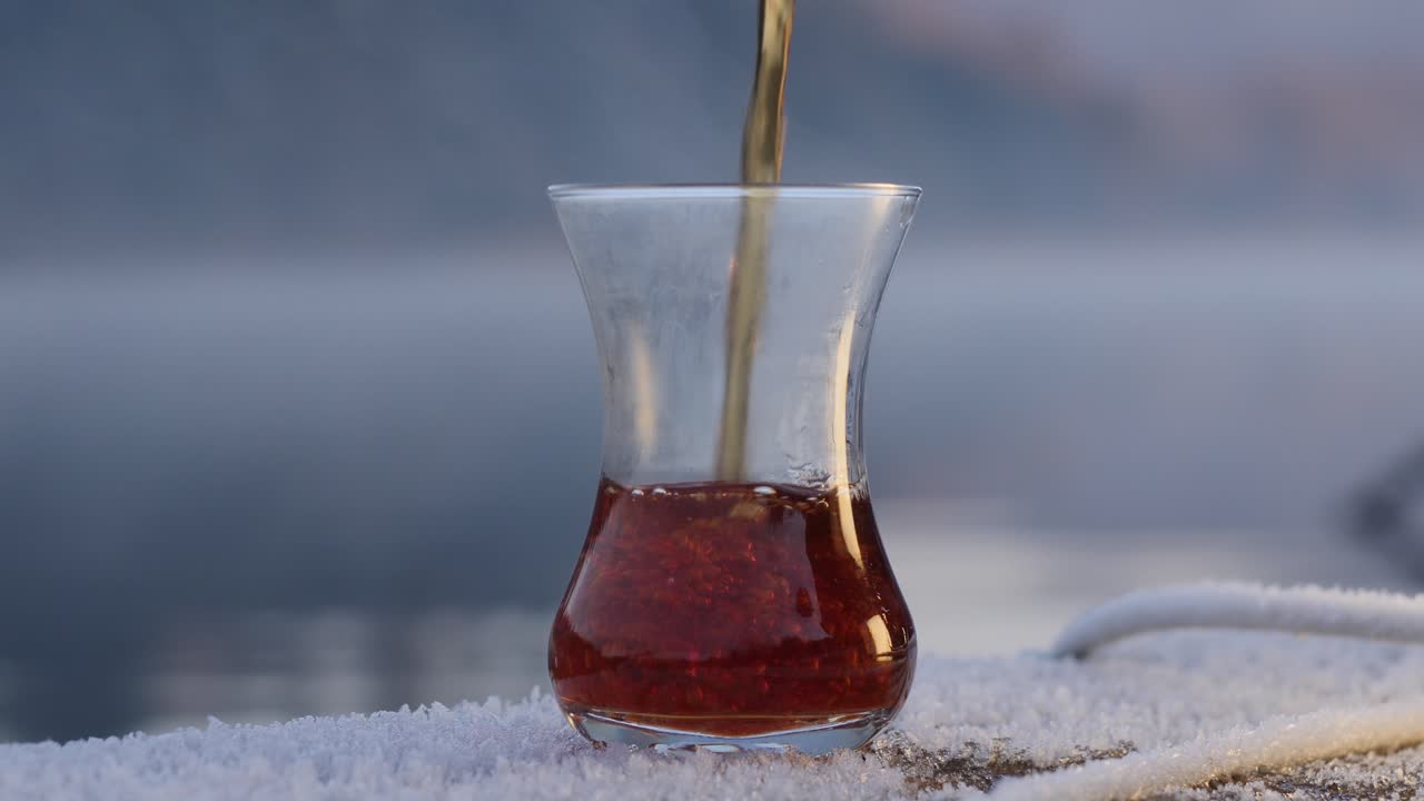 Black chai (tea) pouring into traditional glass on frosty morning
