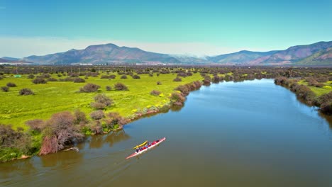 aerial orbit of a rowing team practicing in the caren lagoon on a sunny and clear day with mountains in the background, santiago, chile.