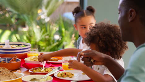 multi-generation family sitting around table at home enjoying meal together