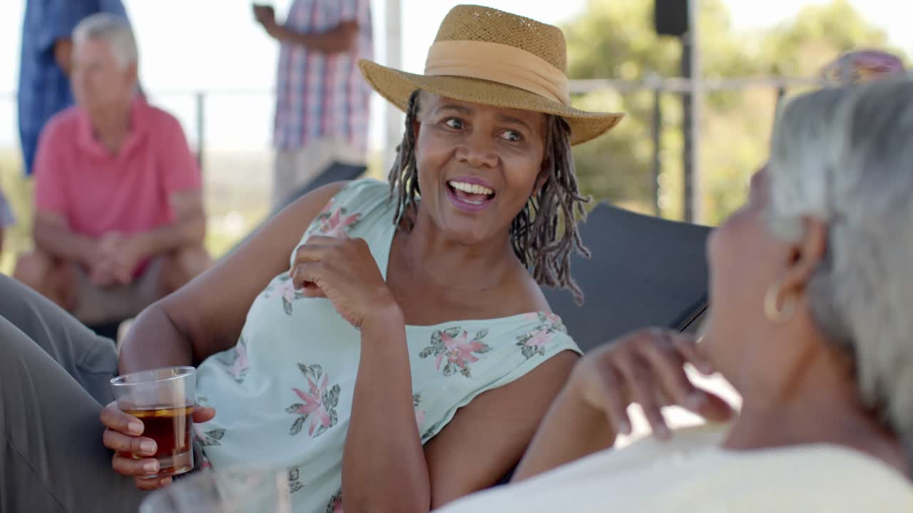 楽しい多様な高齢の女性友達が ガーデンパーティーで飲み物を飲みながら 話し合っています 変化なしで スローモーションで