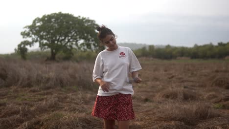 Young-woman-standing-in-a-grassy-field-during-sunset