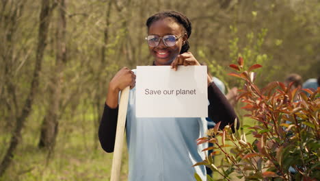 portrait of african american activist holding poster with save our planet message
