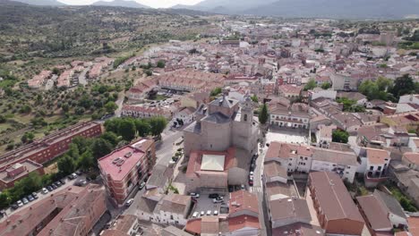Aerial view circling San Mart&iacute;n de Valdeiglesias parish church among idyllic Spanish town neighbourhood streets