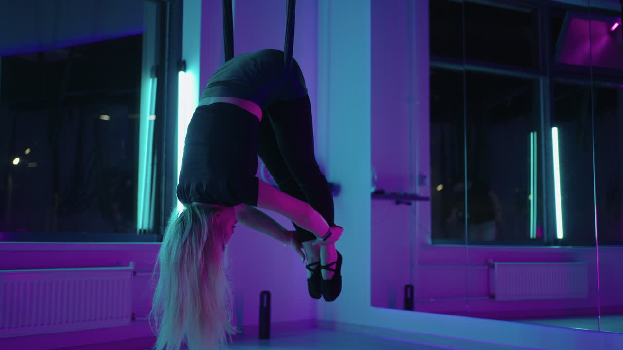 현대적인 플라이 요가 여성이 머리를 아래로 매달고 있습니다.