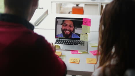 Smiling-bearded-man-talking-with-colleagues-through-laptop.