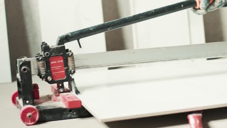 construction worker cutting tiles with tile cutter