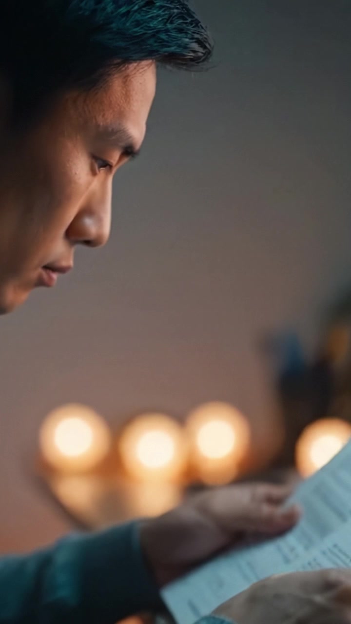 A contemplative man engrossed in reading a document, illuminated by soft candlelight, embodying focus and introspection in a serene atmosphere.