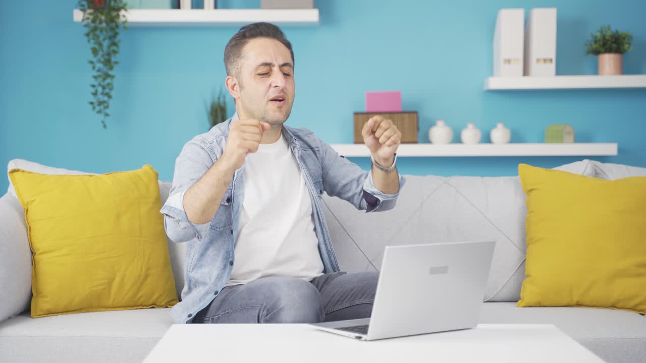 노트북을 보는 남자는 행복하고 춤을 추고 있습니다.