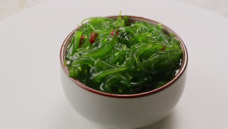 japanese wakame chuka fermented food. close-up on a detail of hiyashi wakame chuka or seaweed salad or seaweed with sesame seeds on a plate. top view. seafood background. health concept.