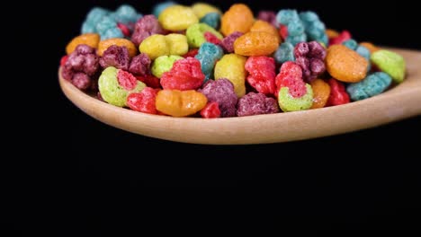 vibrant cereal pieces tumble from a spoon against a black background, captured in slow motion for a dynamic visual effect