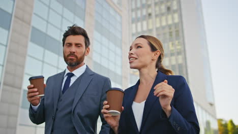 relaxed business couple walking street with coffee close up. smiling coworkers