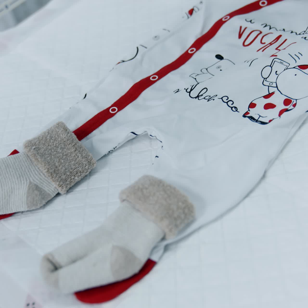 Cute baby bodysuit, red cap and warm socks. Clothes prepared for a newborn baby in hospital