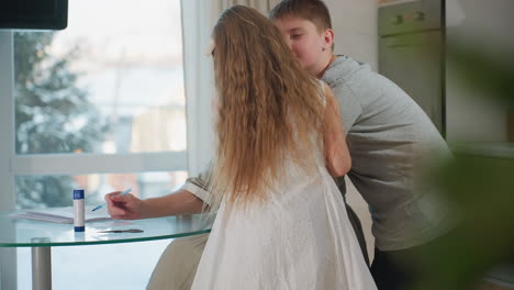 young children hug their mom from the back while she sits on chair, then they sit in front of her after hugging, a heartwarming family moment with love and affection in a cozy indoor setting