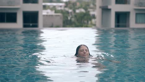 Una-Dama-Sonriente-Emerge-Del-Agua-En-La-Piscina-A-Cámara-Lenta