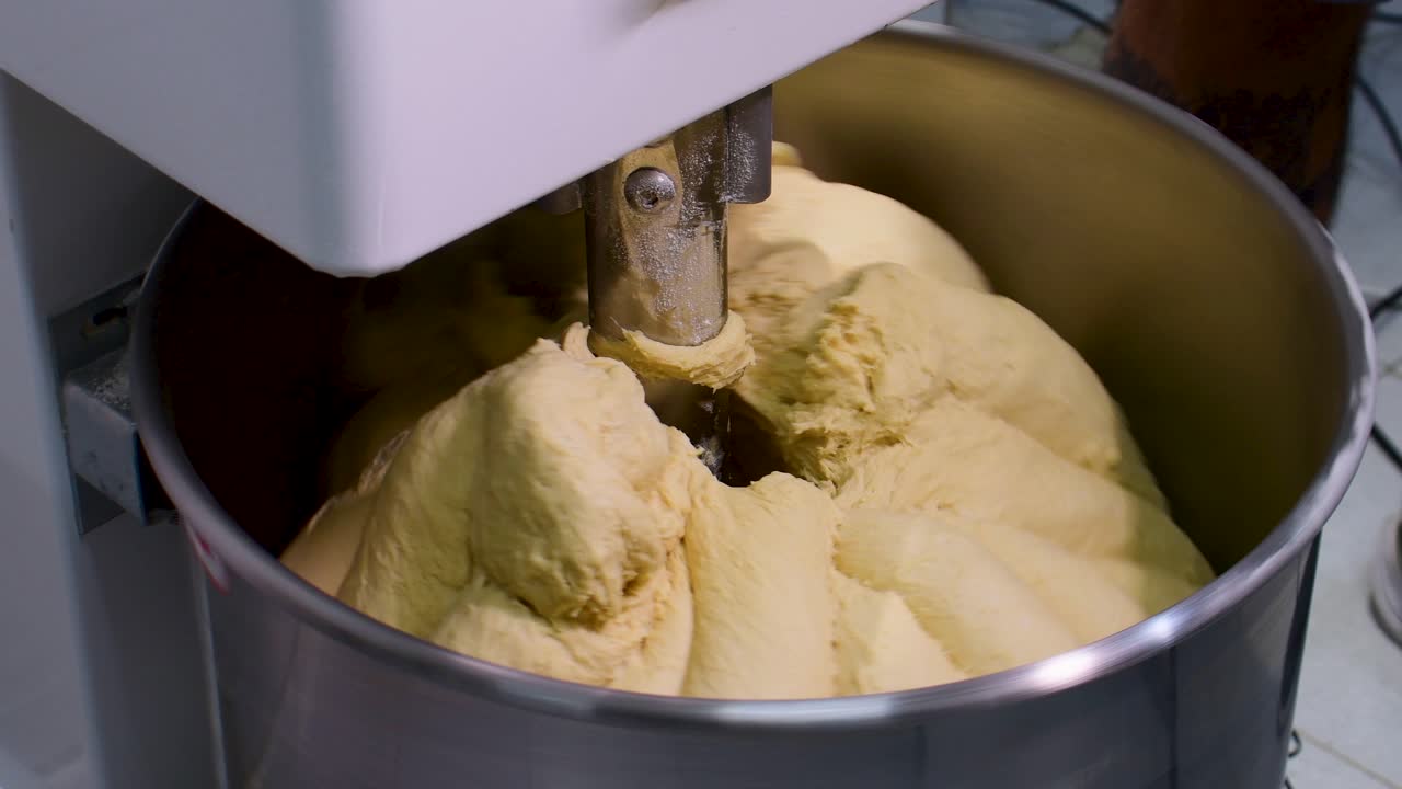 Primo piano della miscelazione dell'impasto in un ambiente di cucina industriale.