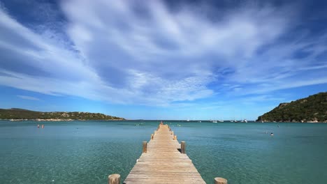 avanzando sobre el largo muelle de madera de la famosa y popular playa de santa giulia en córcega con agua de mar azul prístina