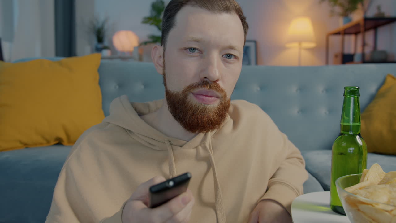 Mand slapper af på sofaen og ser tv