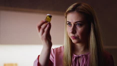 Cruel-wife-looks-at-bottle-with-poisonous-powder-in-kitchen