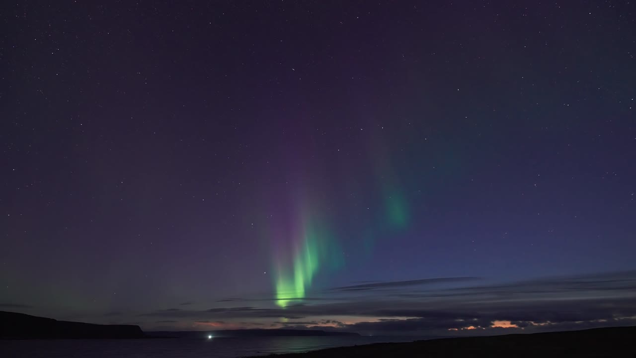겨울 하늘에서 북극광의 매혹적인 춤은 피오르드의 어두운 조용한 물을 조명합니다.