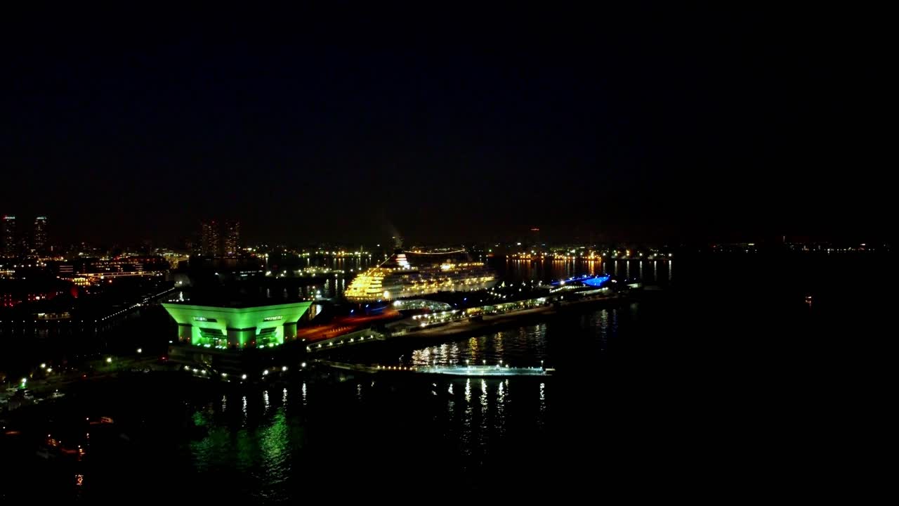 빛나는 건물들이 물 위에 반사되는 도시 스카이라인의 야간 풍경, 활기찬, 높은 각도