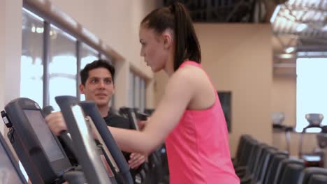 Man-and-woman-using-the-cross-trainers-in-gym